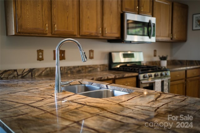 kitchen featuring brown cabinets, appliances with stainless steel finishes, and a sink