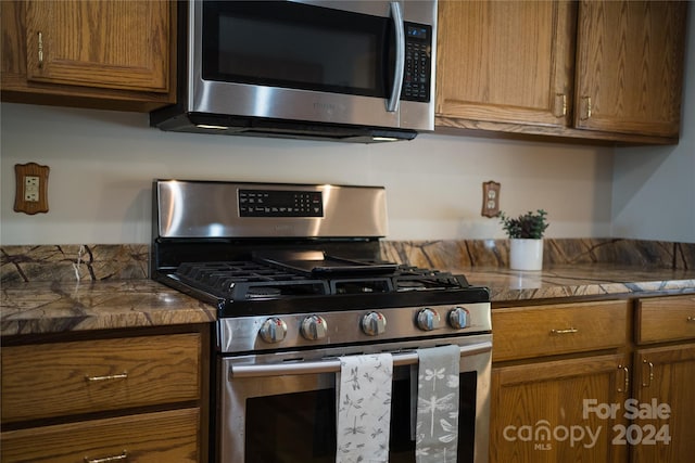 kitchen featuring dark countertops, appliances with stainless steel finishes, and brown cabinetry