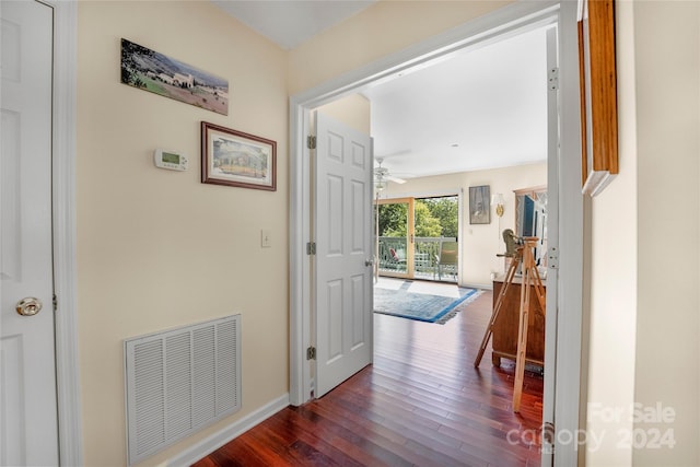 hall featuring visible vents, baseboards, and wood-type flooring