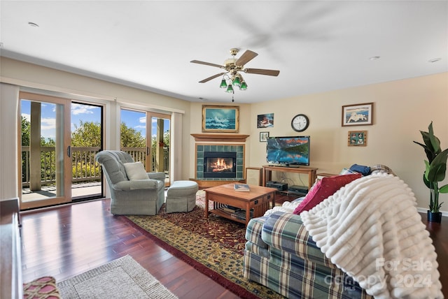 living area with a tiled fireplace, wood finished floors, and a ceiling fan