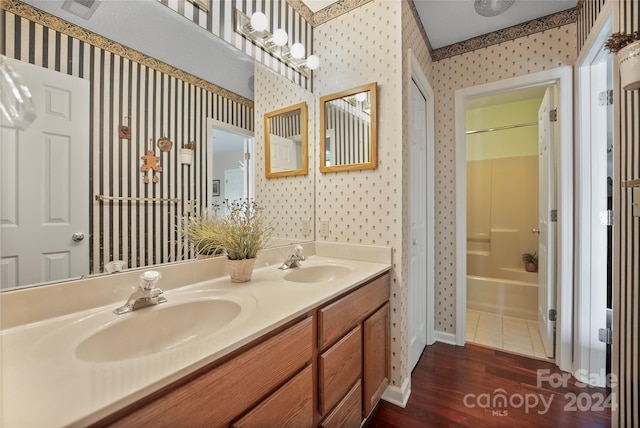 bathroom featuring double vanity, wallpapered walls, shower / bathtub combination, and a sink