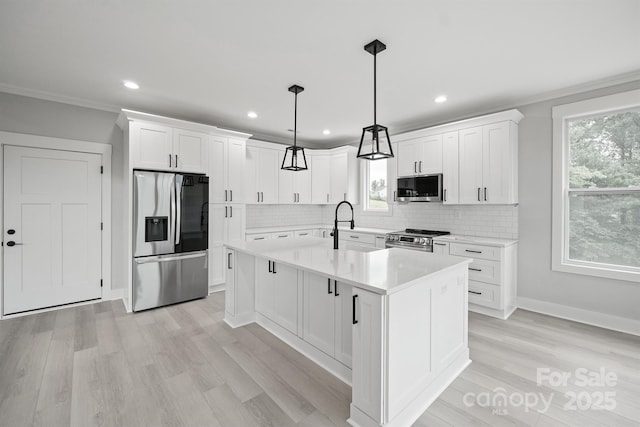 kitchen with white cabinetry, ornamental molding, pendant lighting, stainless steel appliances, and a kitchen island with sink