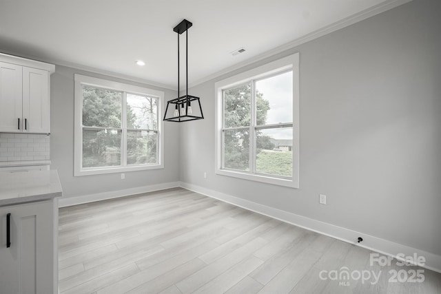 unfurnished dining area with ornamental molding and light hardwood / wood-style floors