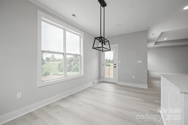 unfurnished dining area featuring ornamental molding and light hardwood / wood-style flooring