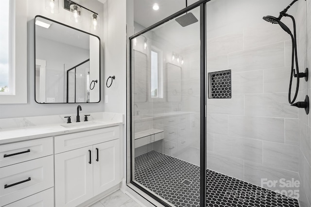 bathroom featuring a shower with door and vanity