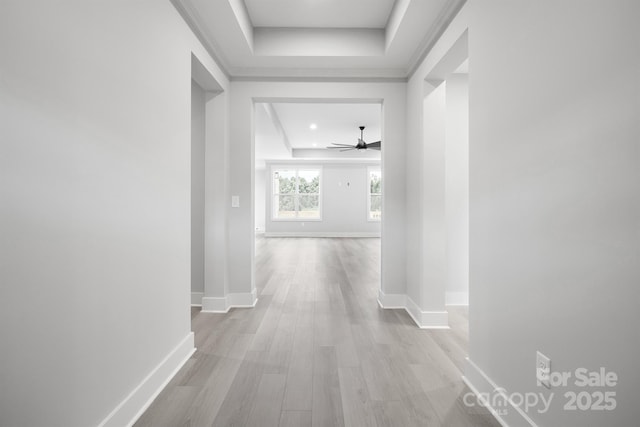 corridor with a raised ceiling and light hardwood / wood-style floors