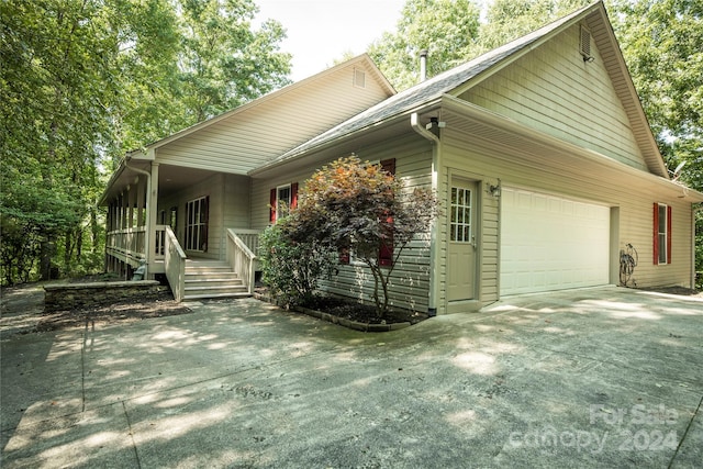 view of side of home featuring covered porch and a garage