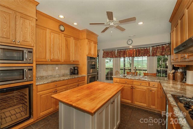 kitchen with stainless steel appliances, backsplash, a center island, wood counters, and sink