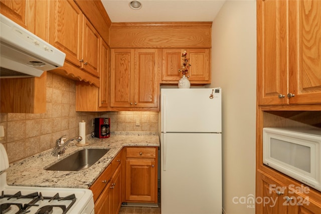 kitchen with light stone countertops, sink, white appliances, and decorative backsplash