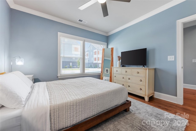 bedroom with ceiling fan, ornamental molding, and wood-type flooring