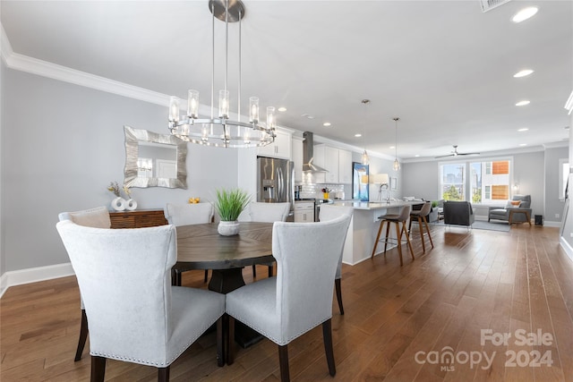 dining space with ornamental molding, hardwood / wood-style floors, and an inviting chandelier