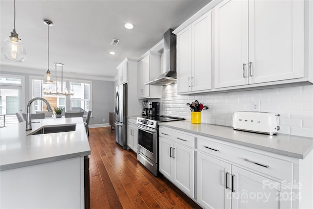 kitchen with wall chimney exhaust hood, sink, white cabinetry, appliances with stainless steel finishes, and pendant lighting