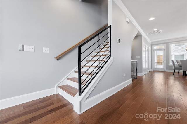 stairs with hardwood / wood-style flooring and crown molding