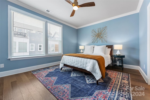 bedroom featuring multiple windows, dark hardwood / wood-style floors, ceiling fan, and ornamental molding