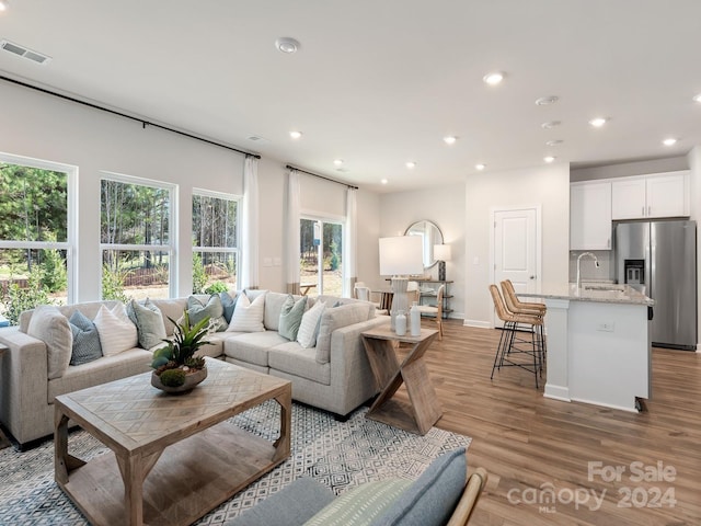 living room featuring baseboards, recessed lighting, visible vents, and light wood-style floors