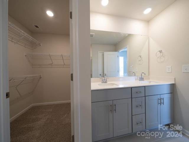 full bath with double vanity, a spacious closet, baseboards, and a sink