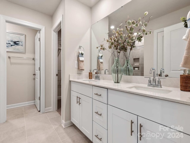 bathroom featuring tile patterned flooring, a sink, baseboards, and double vanity