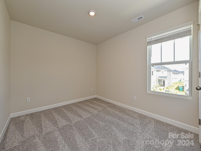 carpeted spare room featuring visible vents and baseboards