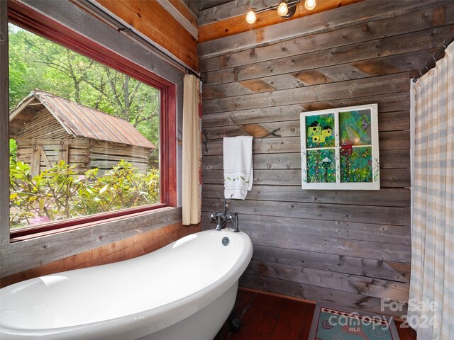 bathroom with wood walls, a bathing tub, and plenty of natural light