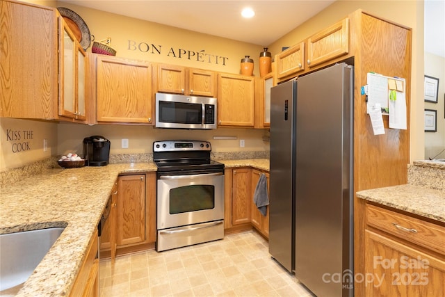 kitchen featuring light stone countertops, sink, and stainless steel appliances