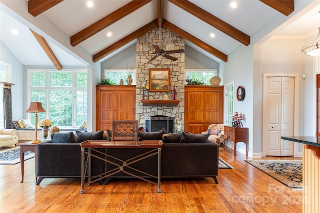 living room featuring high vaulted ceiling, light wood-type flooring, beam ceiling, and a stone fireplace