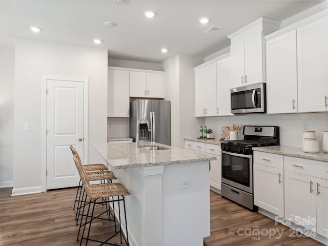 kitchen featuring tasteful backsplash, a center island with sink, stainless steel appliances, and hardwood / wood-style floors