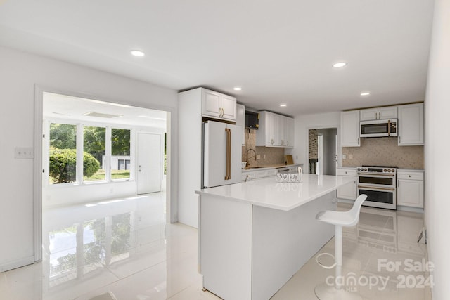 kitchen featuring light tile patterned flooring, white cabinetry, premium appliances, and decorative backsplash