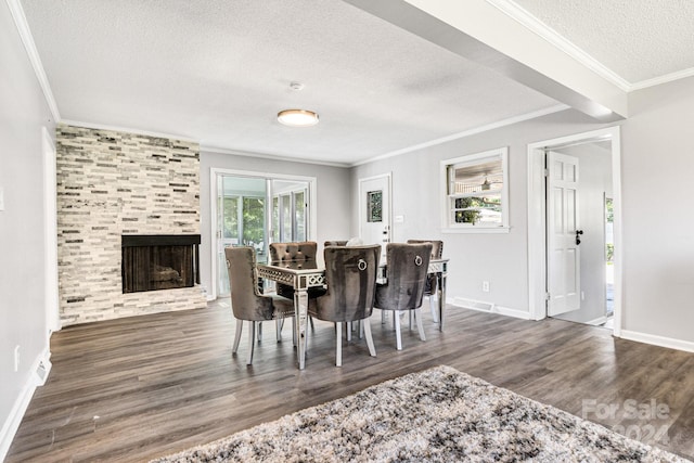 dining space with a textured ceiling, a tiled fireplace, crown molding, and wood-type flooring