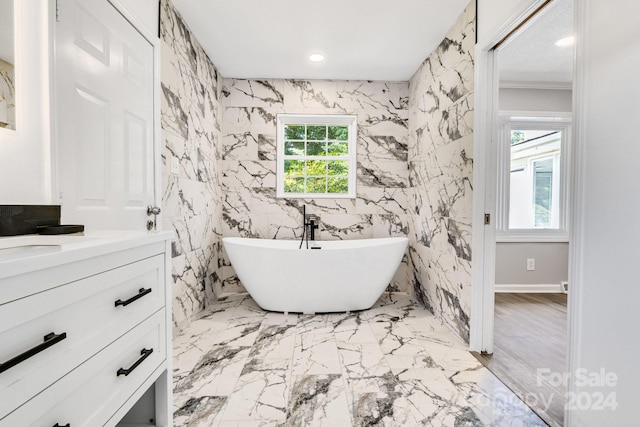 bathroom with hardwood / wood-style flooring, a bathing tub, vanity, and a healthy amount of sunlight