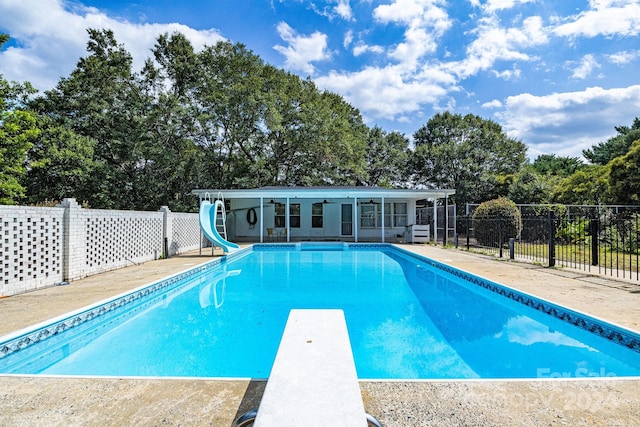 view of swimming pool featuring a diving board and a water slide