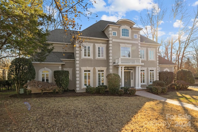 view of front of house featuring a balcony and a front lawn