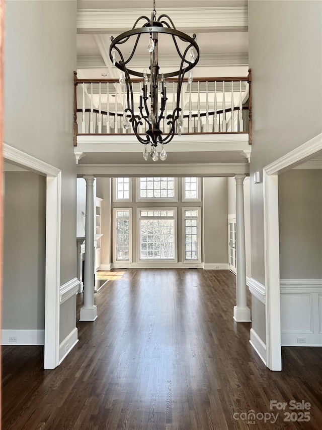 foyer entrance with ornate columns, a high ceiling, ornamental molding, and a notable chandelier