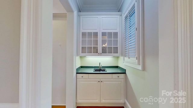 bar featuring crown molding, wet bar, and a sink