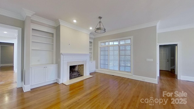 unfurnished living room featuring a fireplace with raised hearth, built in features, light wood-style flooring, and baseboards