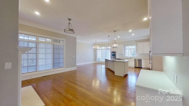 kitchen featuring white cabinets, a kitchen island, appliances with stainless steel finishes, hanging light fixtures, and light countertops