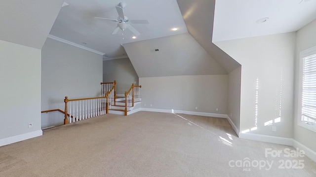 additional living space with lofted ceiling, a ceiling fan, light carpet, plenty of natural light, and baseboards