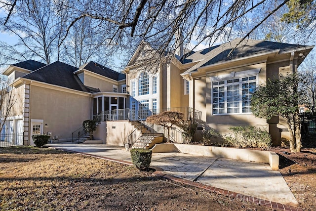 view of front facade with a sunroom, stairway, a patio, and stucco siding