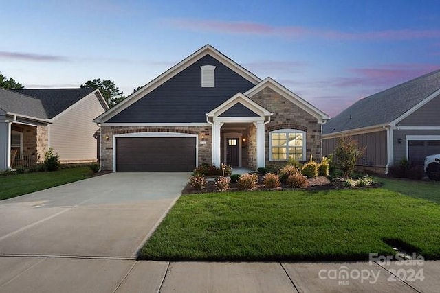 craftsman inspired home featuring an attached garage, driveway, stone siding, and a front lawn