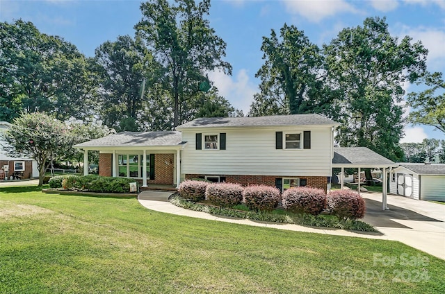 tri-level home featuring a carport, an outdoor structure, a garage, and a front lawn