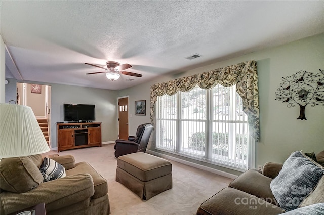 carpeted living room with ceiling fan and a textured ceiling