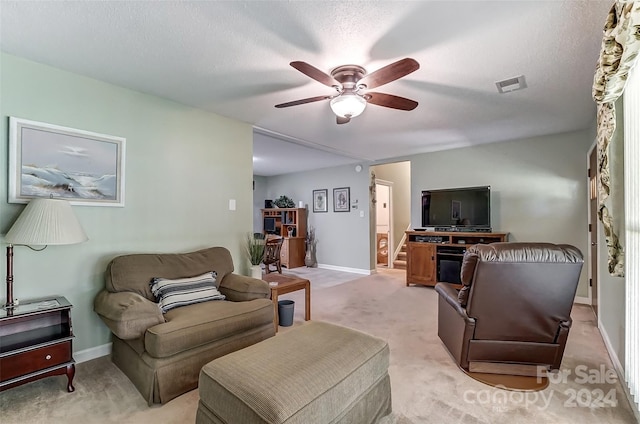 living room with a textured ceiling, light colored carpet, and ceiling fan