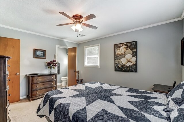 carpeted bedroom with ensuite bath, ceiling fan, and ornamental molding