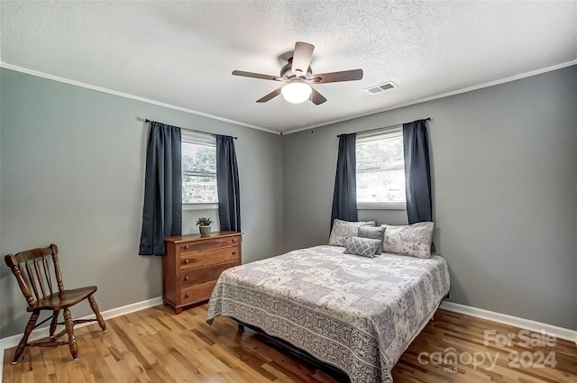 bedroom with a textured ceiling, wood-type flooring, ceiling fan, and crown molding