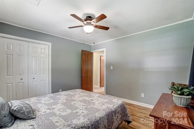 bedroom with ornamental molding, a closet, wood-type flooring, and ceiling fan