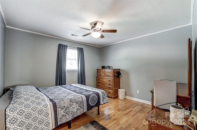 bedroom featuring a textured ceiling, ornamental molding, light wood-type flooring, and ceiling fan