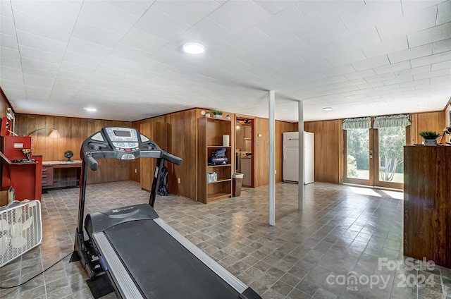 workout room with tile patterned flooring, wooden walls, and french doors