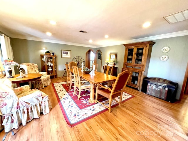 dining space featuring light hardwood / wood-style floors and crown molding