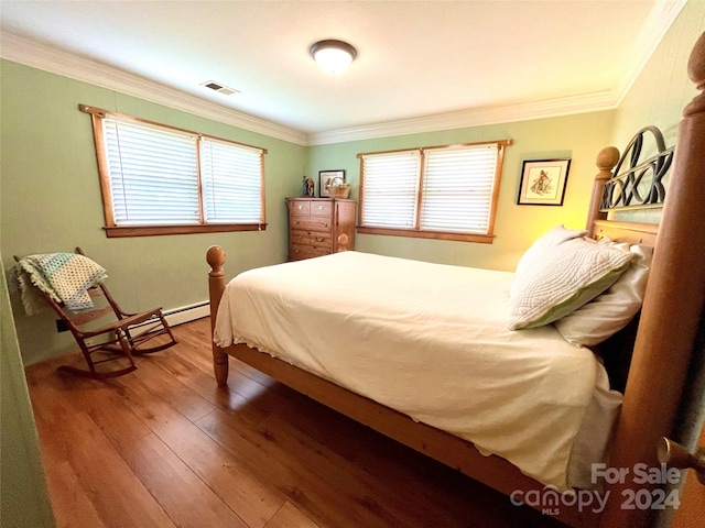 bedroom featuring baseboard heating, multiple windows, crown molding, and wood-type flooring