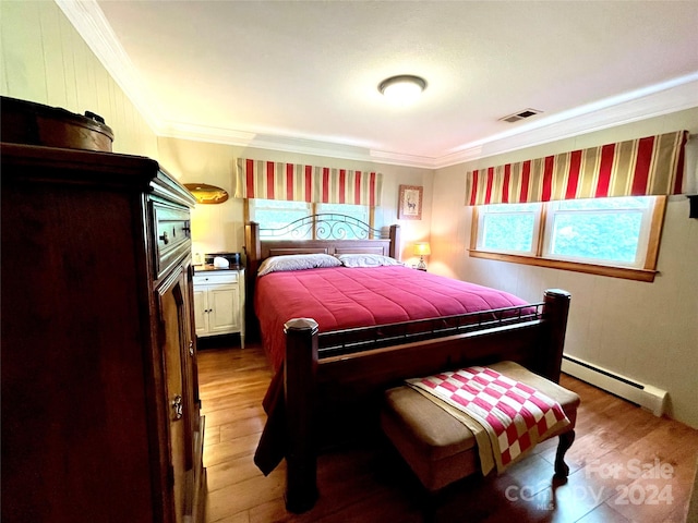 bedroom featuring hardwood / wood-style flooring, ornamental molding, multiple windows, and a baseboard heating unit