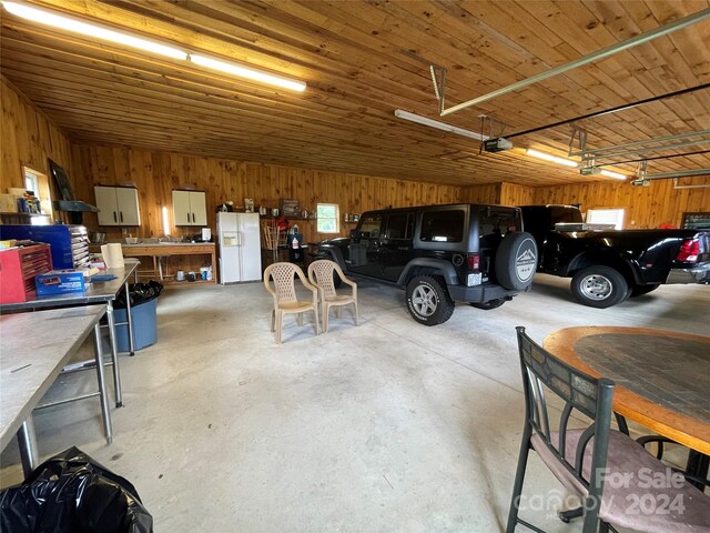 garage featuring wood ceiling, wood walls, white fridge with ice dispenser, and a garage door opener